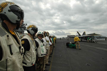 Pacific Ocean (March 3, 2005) - The officers and Sailors, assigned to the Royal Maces of Strike Fighter Squadron Two Seven (VFA-27), line up on the flight deck aboard USS Kitty Hawk (CV 63) to watch their outgoing squadron commanding officer, Cmdr. James Bynum, catapult off the flight deck during a fly-by change of command. Cmdr. Kevin Mannix, VFA-27's former executive officer, took command of the squadron during the fly-by. Currently under way in the 7th Fleet area of responsibility (AOR), Kitty Hawk demonstrates power projection and sea control as the U.S. Navy's only permanently forward-deployed aircraft carrier, operating from Yokosuka, Japan. (U.S. Navy photo by Photographer's Mate 3rd Class Bo Flannigan)